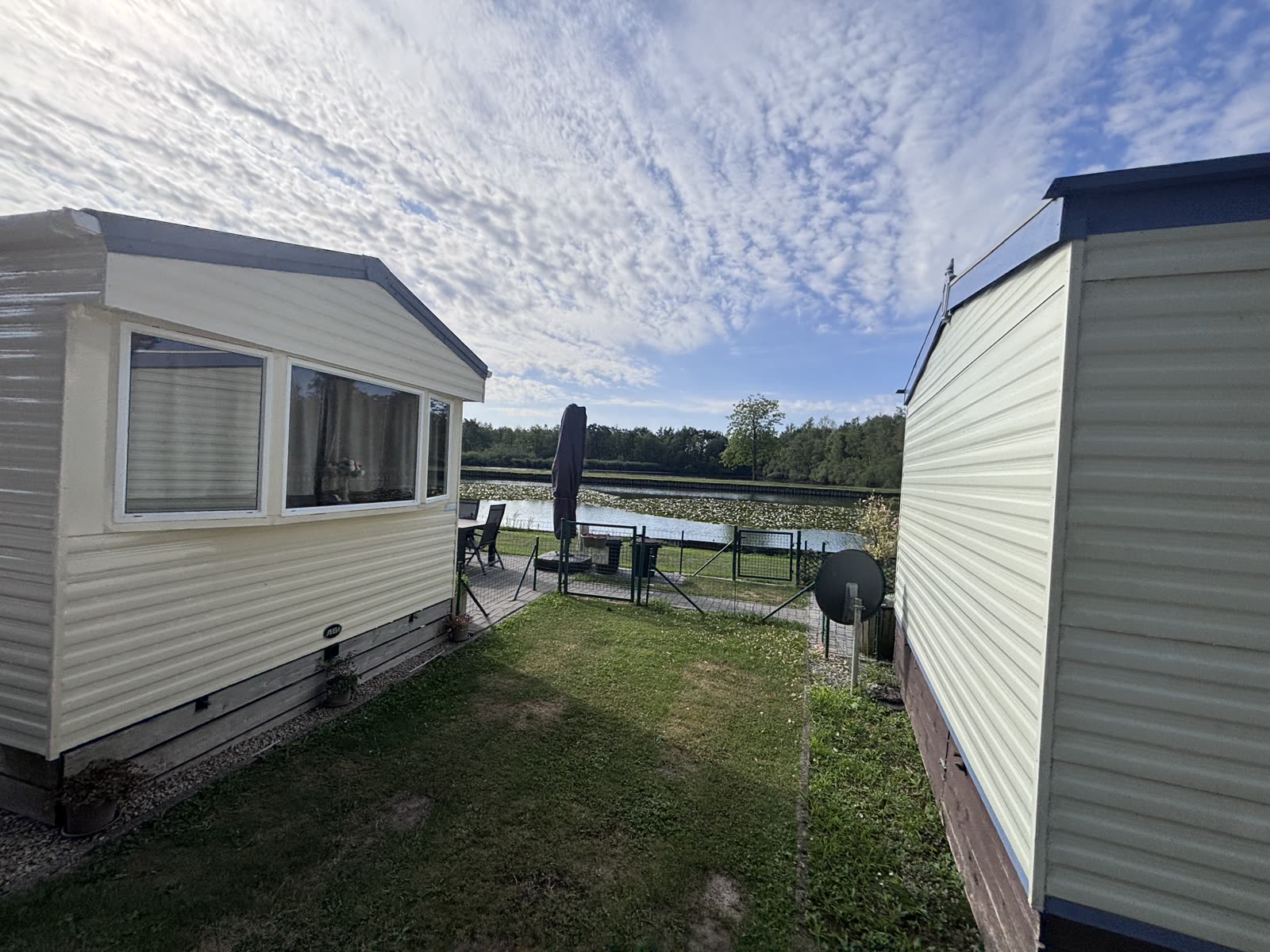 Doorkijkje tussen chalets naar de vijver